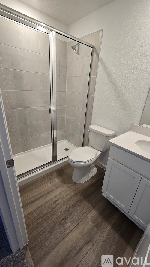 A white toilet sits in a bathroom with a walk-in shower.