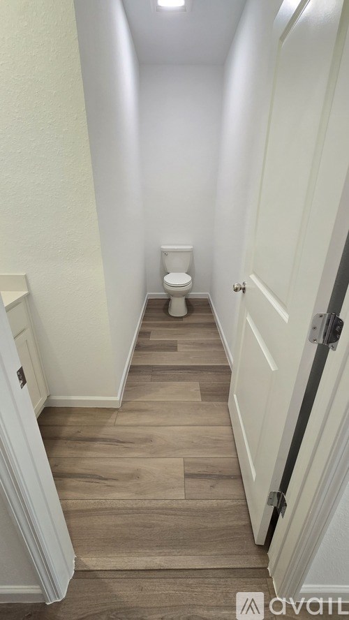 A hallway with a toilet at the end.
