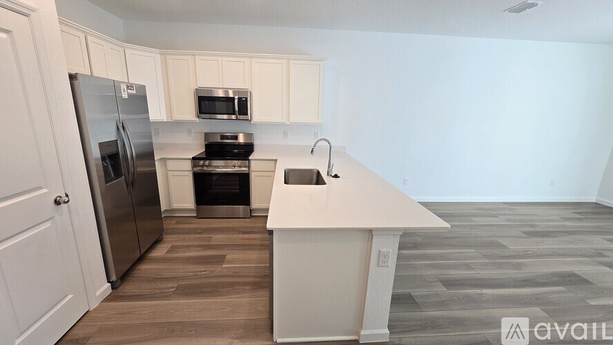 A kitchen with a refrigerator, microwave, oven, and sink.
