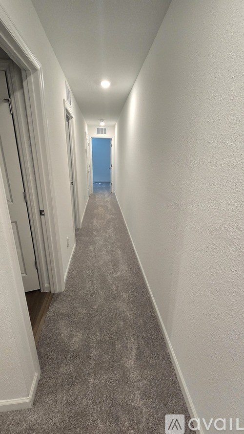 A long hallway with a blue door at the end.