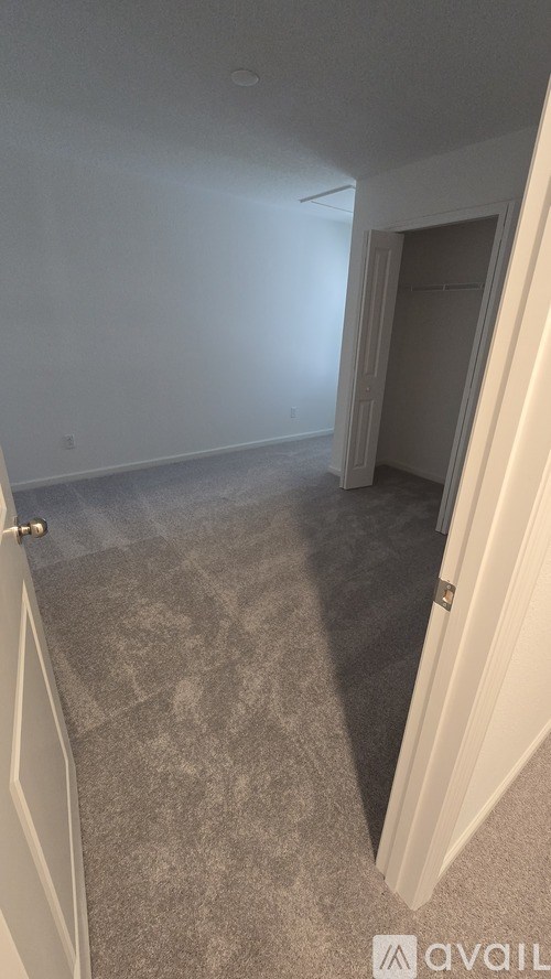 A room with a carpeted floor and a door on the left side.