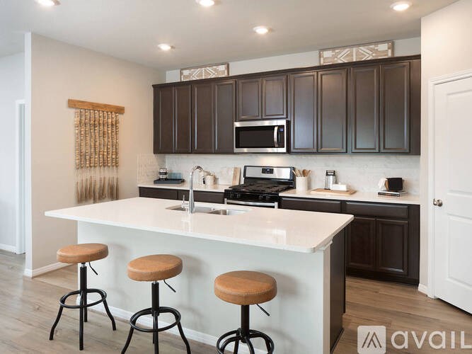 A kitchen with white countertops and dark brown cabinets.