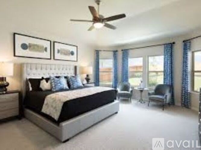 A bedroom with a large bed, a ceiling fan, and a chair.