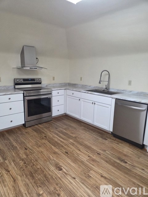 A kitchen with a stainless steel refrigerator, a stove, and a sink.