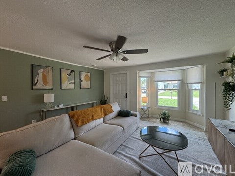 A living room with a grey couch and a ceiling fan.