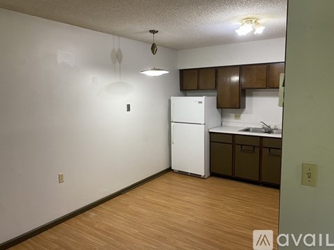 A kitchen with a white refrigerator and wooden floors.