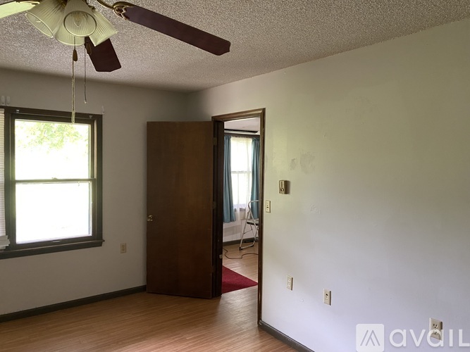 A room with a ceiling fan and a door leading to another room.
