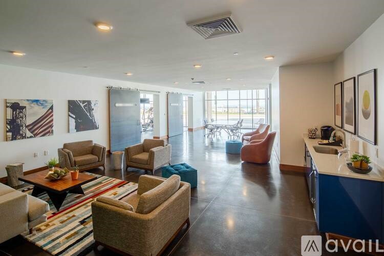 A living room with a variety of seating options and a kitchen area.