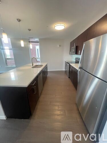 A kitchen with a stainless steel refrigerator and wooden floors.