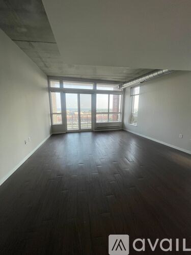 A room with dark wood flooring and a large window.
