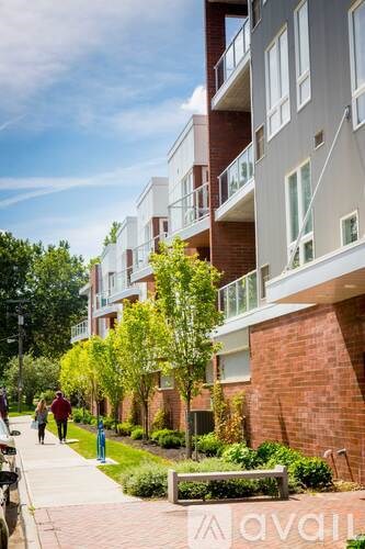 A street view of a residential area with people walking on the sidewalk.