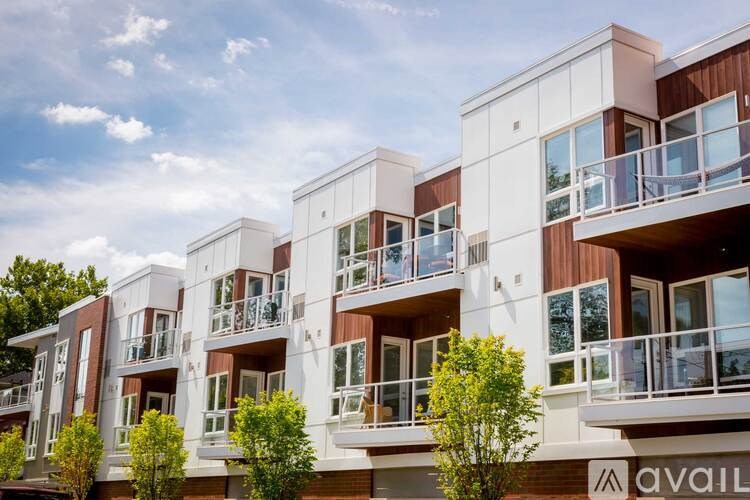 A row of modern townhouses with balconies and trees in front.
