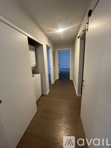 A long hallway with white walls and wooden floors.