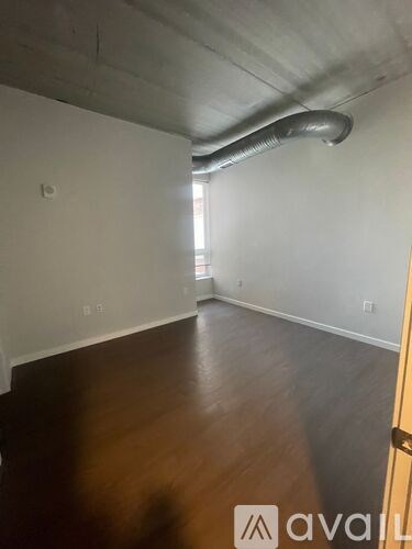 A room with a wooden floor and a metal pipe on the ceiling.
