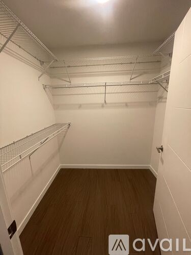 A room with white walls and wooden flooring, with metal shelving on the walls.