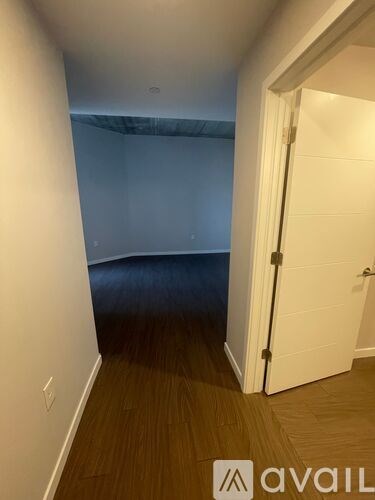 A room with a white door and wooden floor.