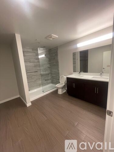 A bathroom with a glass shower door and a wooden floor.