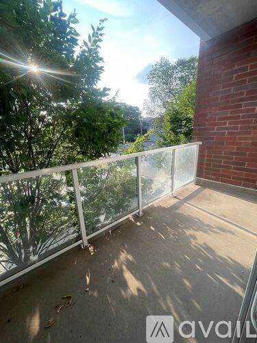 A balcony with a glass railing and trees in the background.