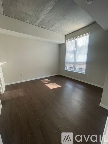A room with wooden flooring and a window letting in sunlight.