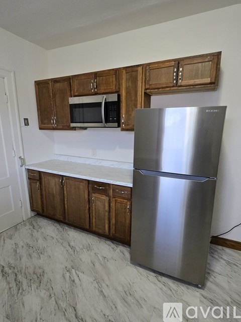 A kitchen with a stainless steel refrigerator and wooden cabinets.
