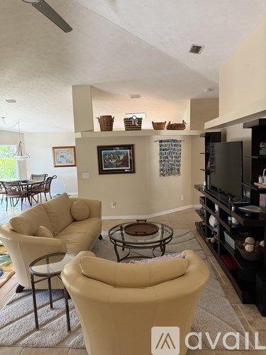 A living room with a beige sofa and a glass coffee table.