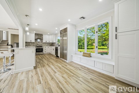 A spacious kitchen with white cabinets and a wooden floor.