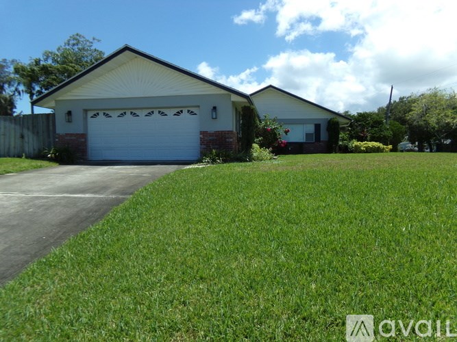 A house with a white garage door is situated in a grassy area.