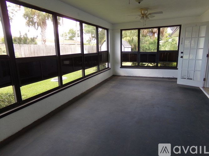 A spacious room with large windows and a ceiling fan.