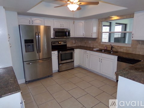 A kitchen with a refrigerator, oven, microwave, and sink.