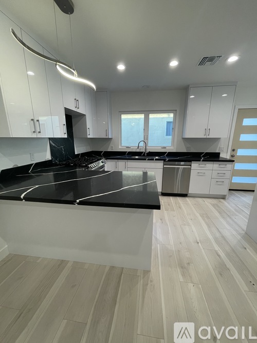 A kitchen with white cabinets and a black refrigerator.