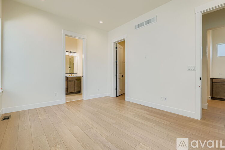 A spacious room with wooden flooring and white walls.