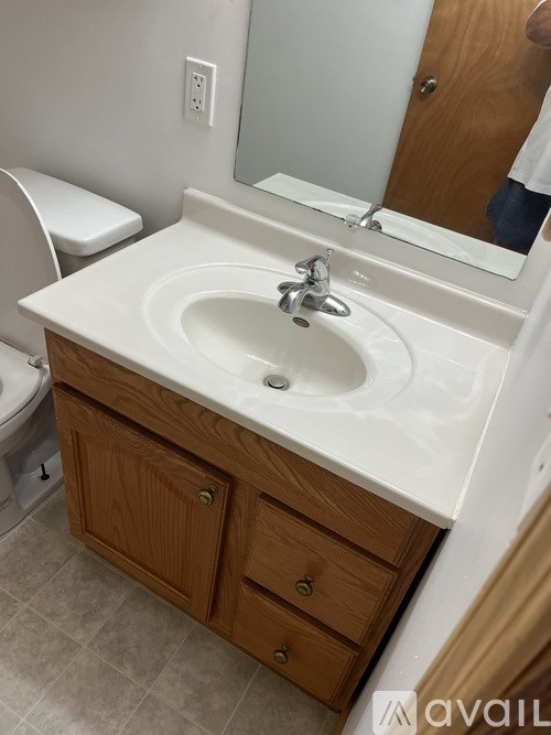 A bathroom with a white sink and wooden cabinets.
