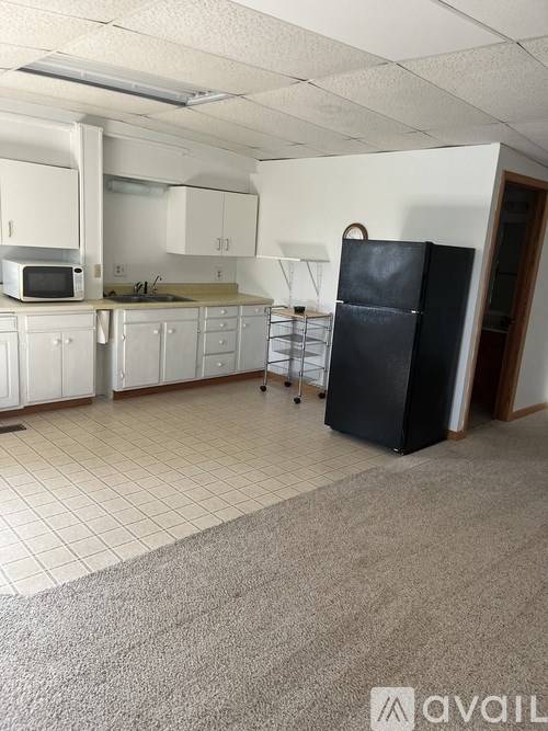 A kitchen with white cabinets and a black fridge.