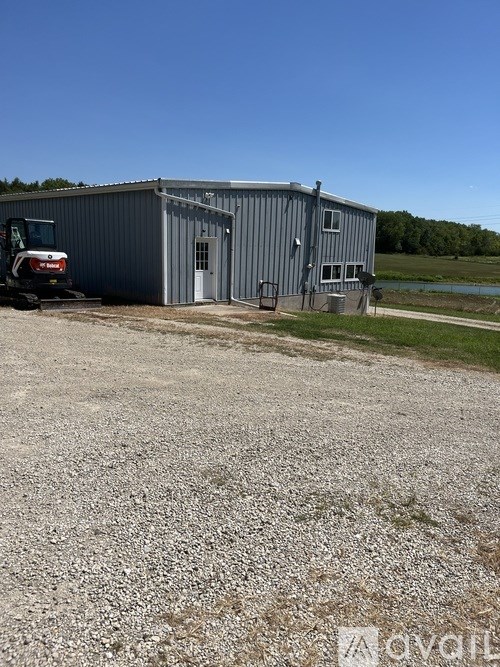A gravel lot with a tractor and a building.