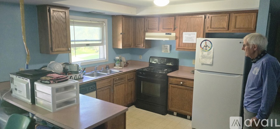 A man stands in a kitchen with a refrigerator and a stove.