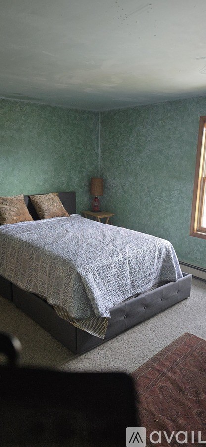 A bedroom with a bed and a small table.