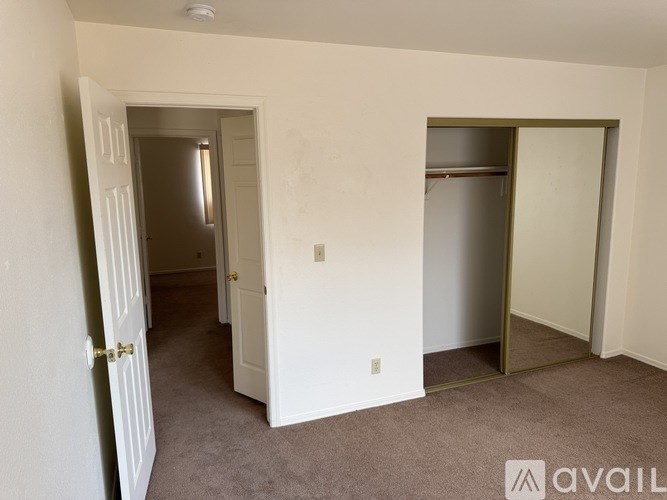 A room with a carpeted floor and two doors, one of which is open.