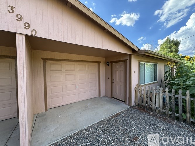 A room with a carpeted floor, a door, and a window with blinds.