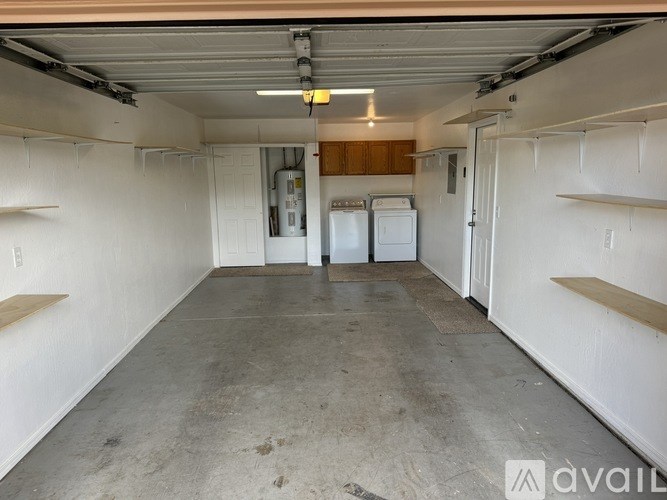 A room with a grey water heater and wooden shelves.
