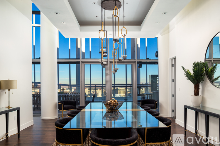 A modern dining room with a glass table and black chairs.