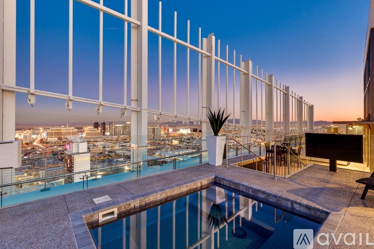 A pool on a balcony with a view of the city at dusk.