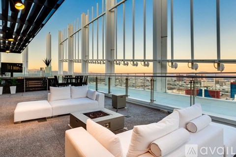 A modern living room with white furniture and a view of the city at dusk.