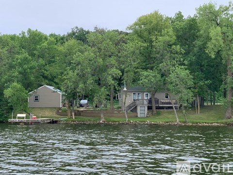 A house is situated on a lake surrounded by trees.