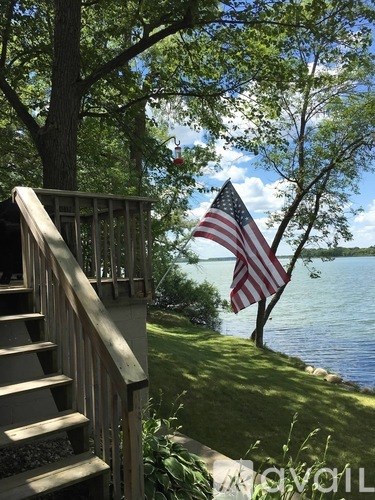 A flag is hanging from a tree by a lake.