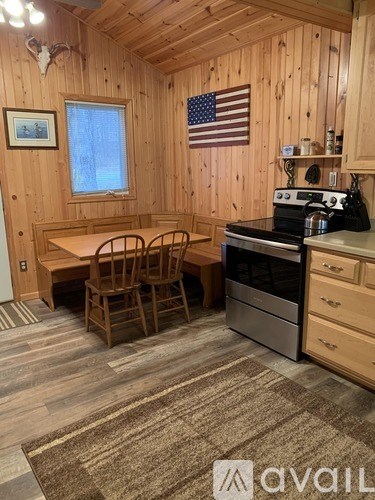 A kitchen area with a table and chairs, a stove, and an American flag hanging on the wall.