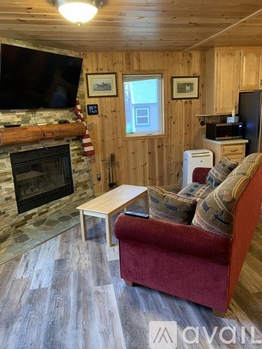 A living room with a red couch and a stone fireplace.