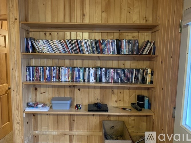 A wooden shelf with DVDs and a box on the lower shelf.