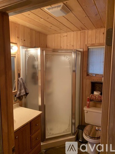A wooden bathroom with a toilet, sink, and shower.