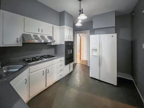 A kitchen with white cabinets and a white refrigerator.