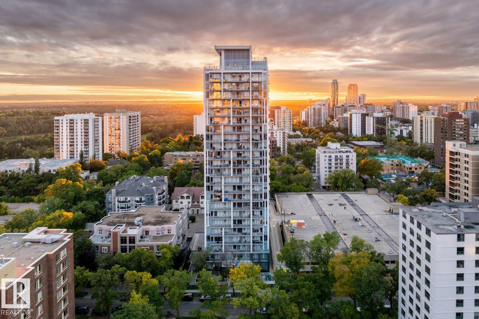 A tall building stands in the middle of a cityscape at sunset.